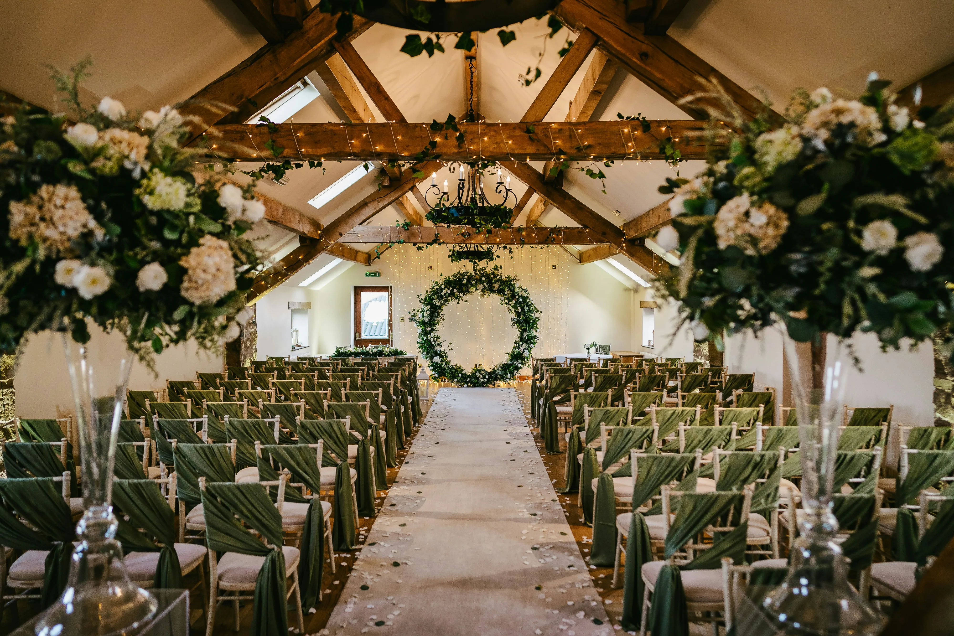 A wedding ceremony room dressed with foliage and flowers before guests arrive.