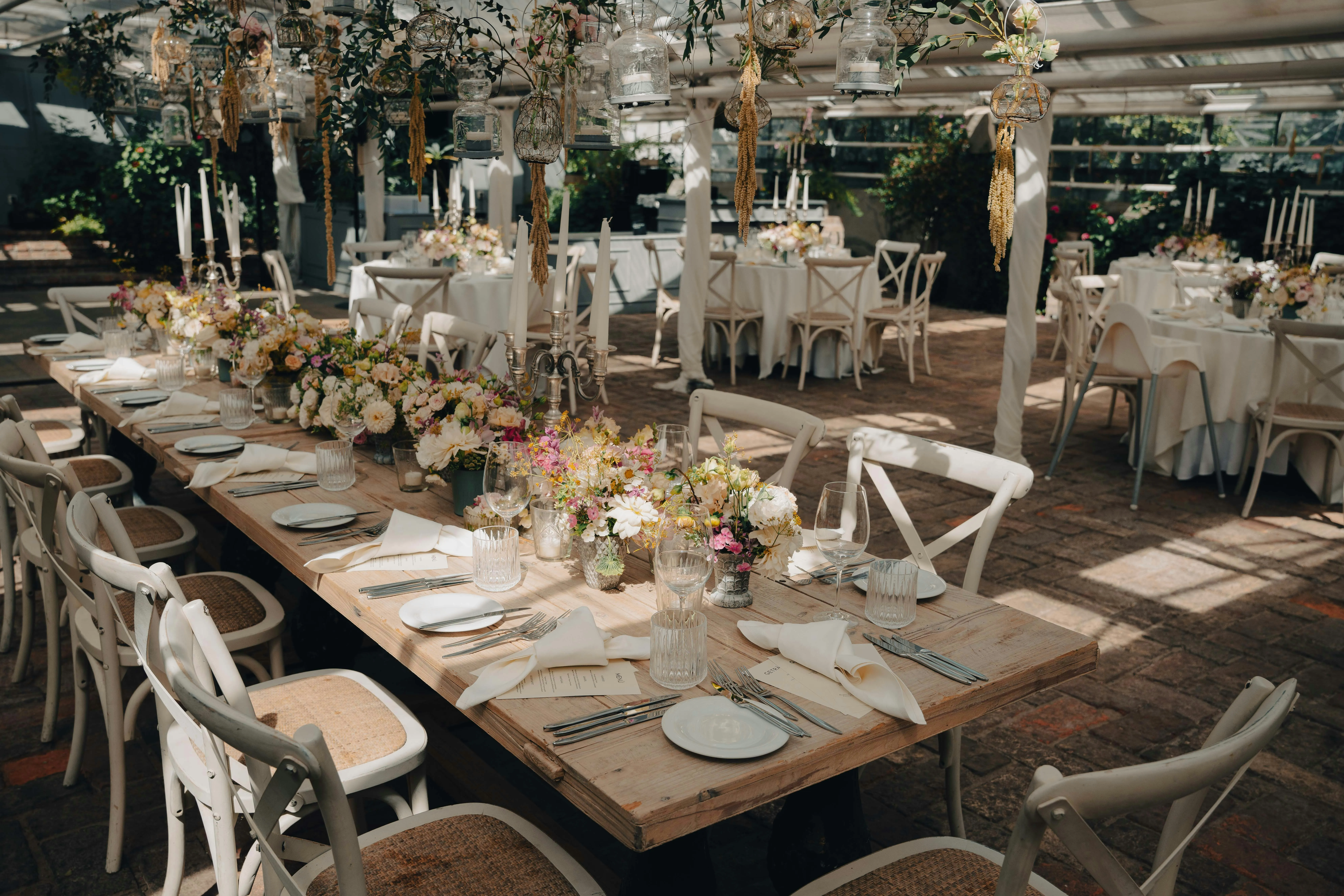 A glasshouse laid for a wedding breakfast, tables dressed and waiting.